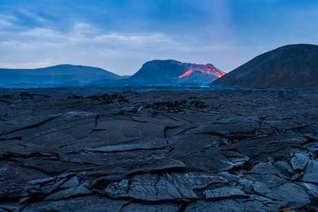 Fresh lava oozing out from under black slabs in Iceland