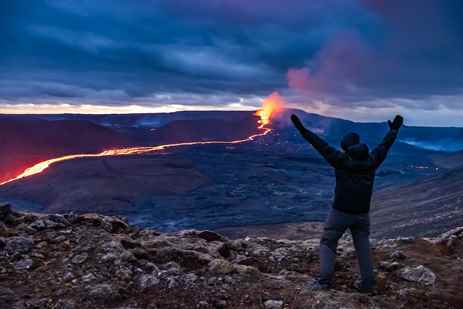 A man throws his hands up in celebration as Iceland's volcano erupts in the distance
