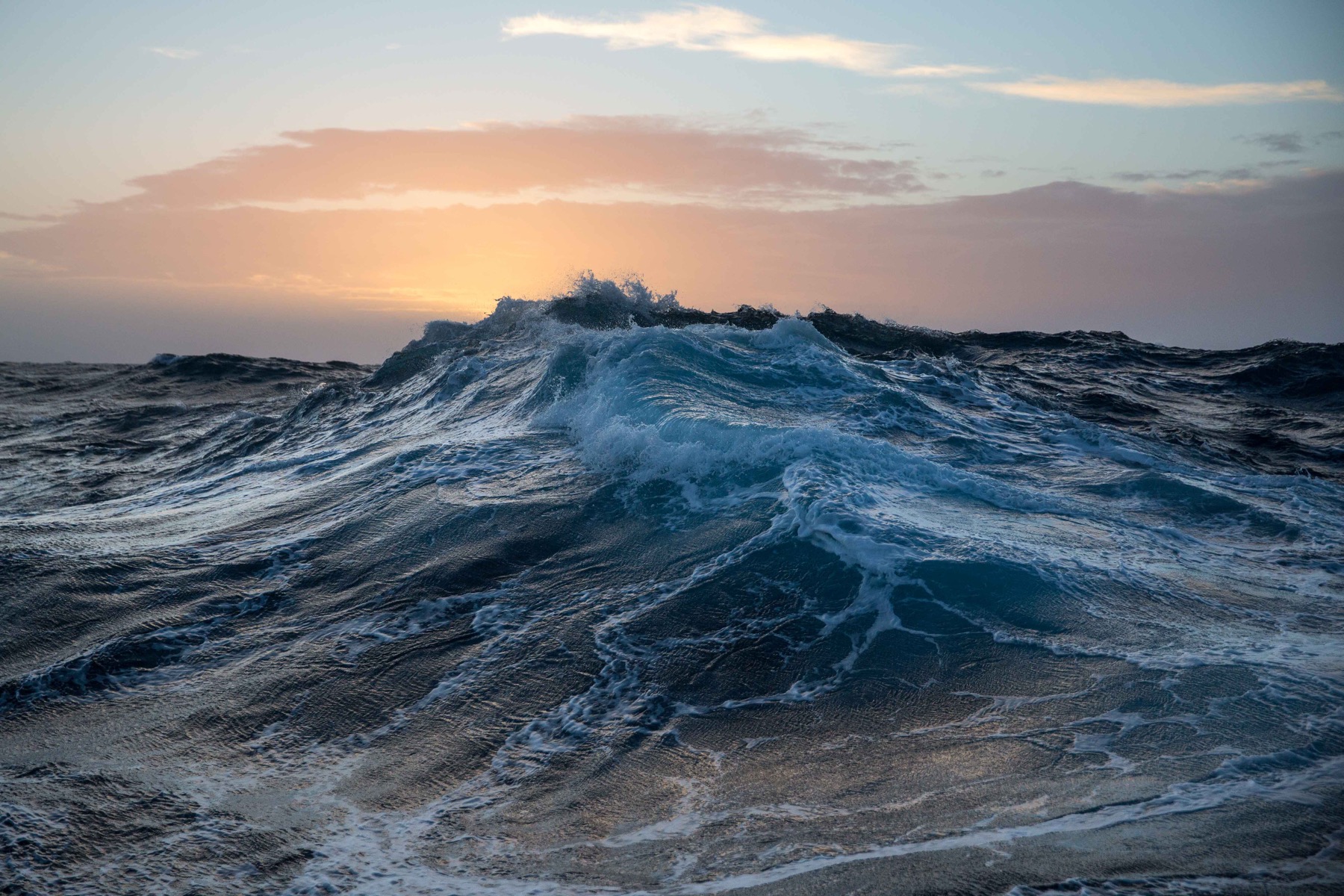 At sunrise; a dark, roiling sea, streaked with spume